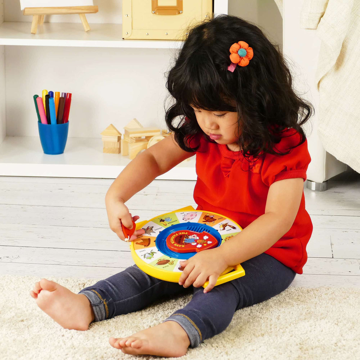 Lifestyle shot of girl sitting on a bedroom floor playing with the See N Say
