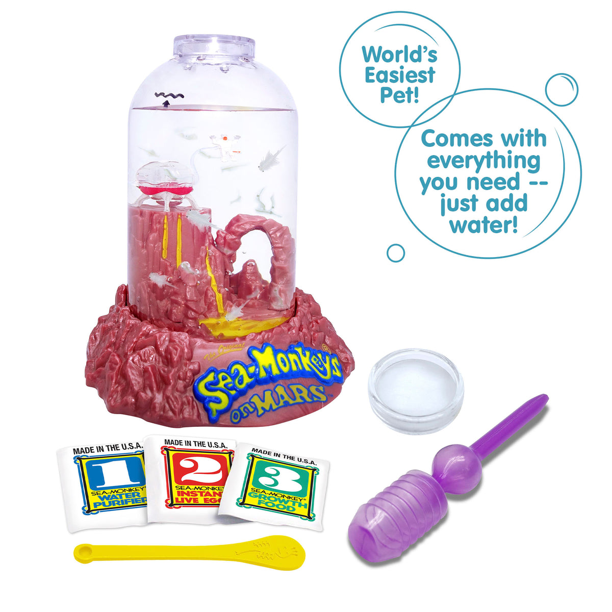 Three packets, numbered 1, 2, and 3 from left to right are vivble in front of the Mars aquarium. There is a small yellow spoon laying in front of the packets, and a purple pipette and clear circle magnifyer next to the spoon. There are two callouts in circles. They read "World's Easiest Pet!", and "Comes with everything you need -- just add water!"