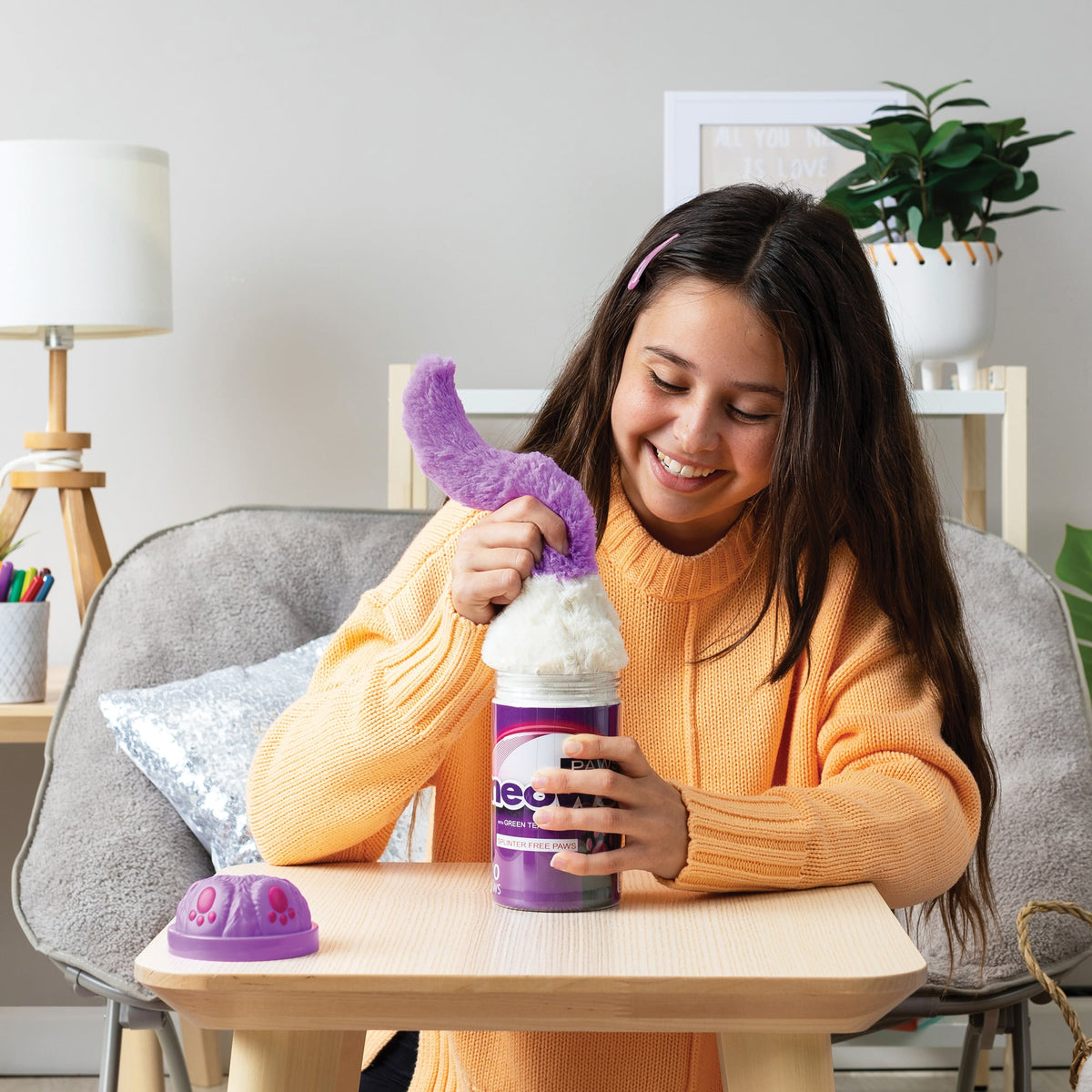 Girl pulling out the plush by the tail smushed into a purple package